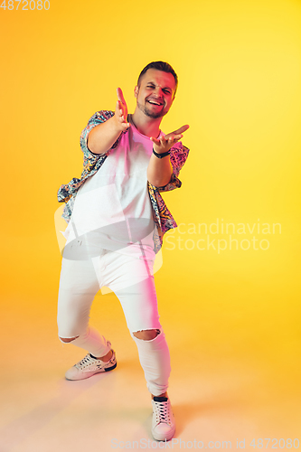 Image of Young caucasian musician, dancer, party host, DJ on gradient background in neon light