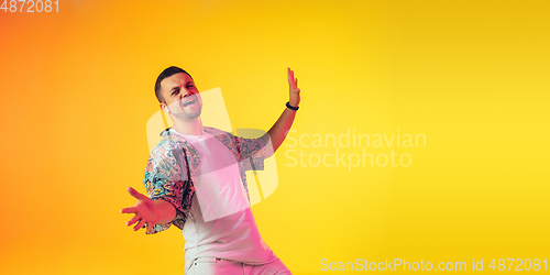 Image of Young caucasian musician, dancer, party host, DJ on gradient background in neon light, flyer with copyspace for ad