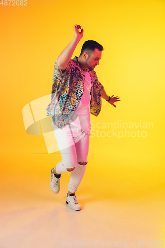 Image of Young caucasian musician, dancer, party host, DJ on gradient background in neon light