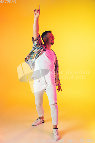 Image of Young caucasian musician, dancer, party host, DJ on gradient background in neon light