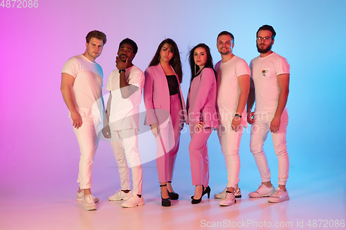 Image of Group of young multiethnic musicians created band, posing in neon light on gradient background