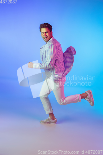 Image of Young caucasian musician, dancer, party host, DJ on gradient background in neon light