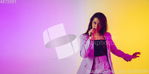 Image of Caucasian female singer portrait isolated on gradient studio background in neon light, flyer with copyspace for ad
