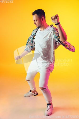 Image of Young caucasian musician, dancer, party host, DJ on gradient background in neon light