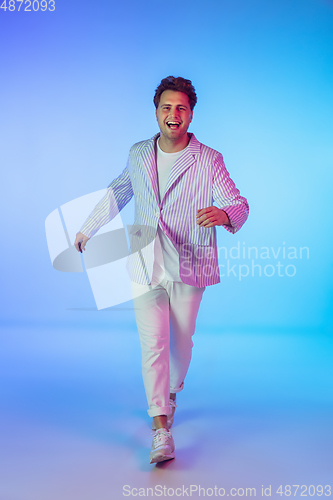 Image of Young caucasian musician, dancer, party host, DJ on gradient background in neon light