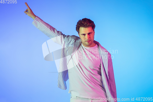 Image of Young caucasian musician, dancer, party host, DJ on gradient background in neon light