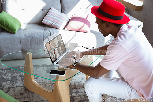 Image of African-american man during videocall with his band sitting at home, musicians during quarantine and insulation