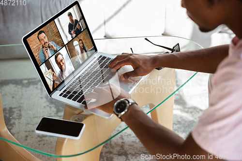 Image of African-american man during videocall with his band sitting at home, musicians during quarantine and insulation