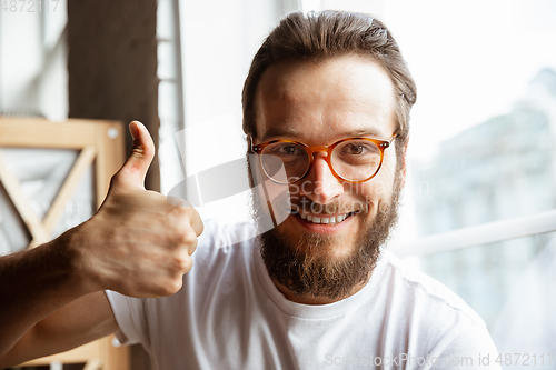 Image of Caucasian musician greeting audience before online concert at home isolated and quarantined, cheerful, smiling