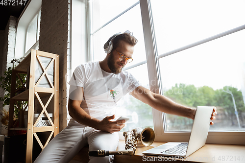 Image of Caucasian musician preparing for concert at home isolated and quarantined, impressive improvising with band connected online