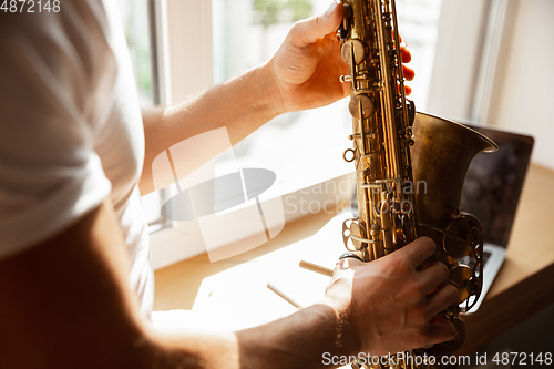 Image of Caucasian musician playing saxophone during concert at home isolated and quarantined, impressive improvising with band connected online