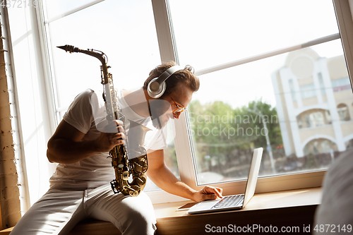 Image of Caucasian musician playing saxophone during online concert at home isolated and quarantined, impressive improvising