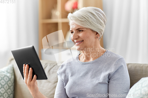 Image of happy senior woman with tablet pc at home