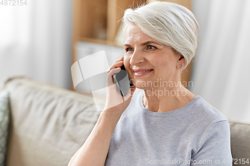 Image of senior woman calling on smartphone at home