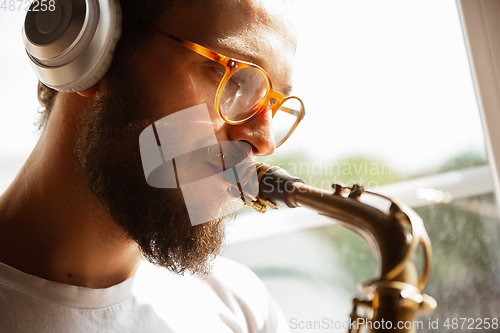 Image of Close up of caucasian musician playing saxophone during concert at home isolated and quarantined