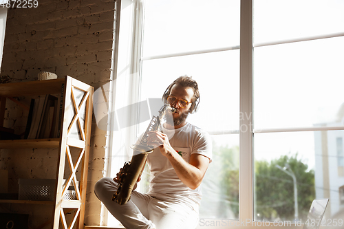 Image of Caucasian musician playing saxophone during online concert at home isolated and quarantined, impressive improvising