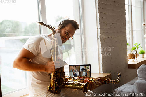 Image of Caucasian musician preparing for concert at home isolated and quarantined, impressive improvising with band connected online