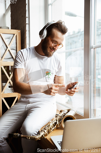 Image of Caucasian musician preparing for concert at home isolated and quarantined, impressive improvising with band connected online