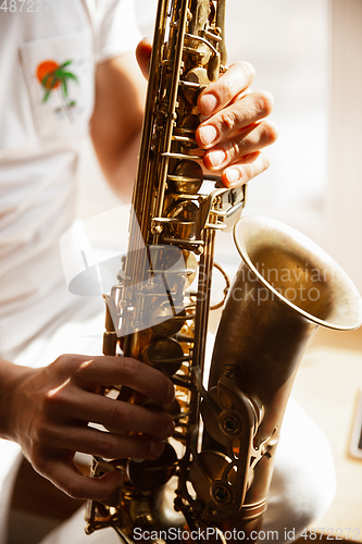 Image of Close up of caucasian musician playing saxophone during concert at home isolated and quarantined