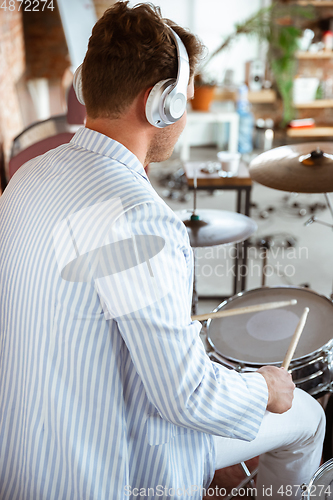 Image of Caucasian musician playing drumms during online concert with the band at home isolated and attented, smiling, cheerful