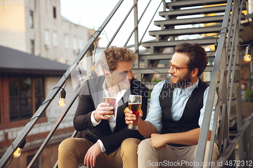 Image of Two men talking, celebrating, look happy, have corporate party at office or bar