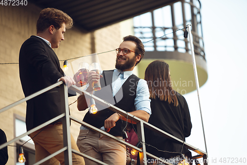 Image of Two men talking, celebrating, look happy, have corporate party at office or bar