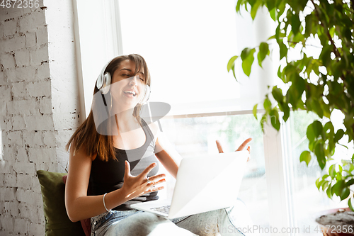 Image of Caucasian female singer during online concert at home insulated and quarantined, cheerful and happy, singing live, performing