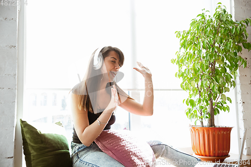 Image of Caucasian female singer during online concert at home insulated and quarantined, cheerful and happy, singing live, performing