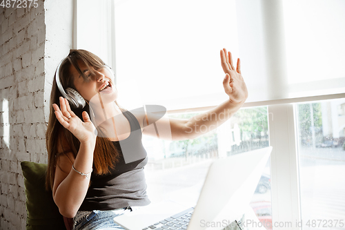 Image of Caucasian female singer during online concert at home insulated and quarantined, cheerful and happy, singing live, performing