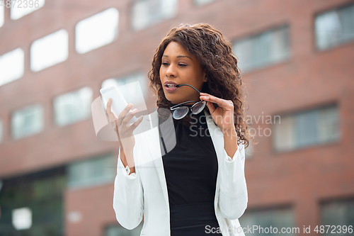 Image of Beautiful african-american well-dressed businesswoman looks confident and busy, successful