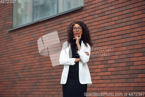 Image of Beautiful african-american well-dressed businesswoman looks confident and busy, successful