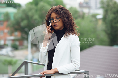 Image of Beautiful african-american well-dressed businesswoman looks confident and busy, successful