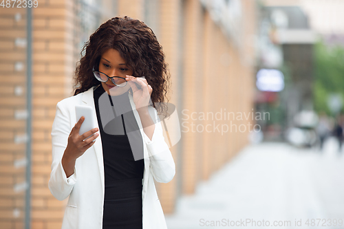Image of Beautiful african-american well-dressed businesswoman looks confident and busy, successful