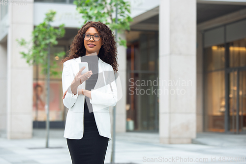 Image of Beautiful african-american well-dressed businesswoman looks confident and busy, successful