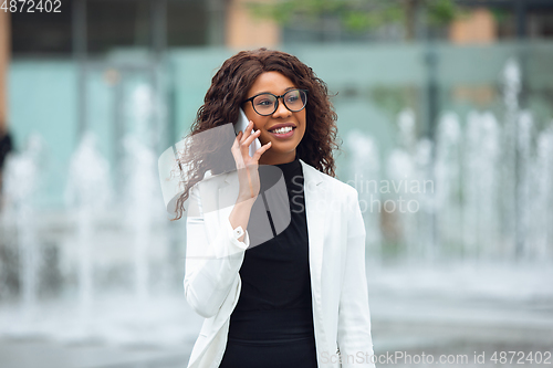 Image of Beautiful african-american well-dressed businesswoman looks confident and busy, successful