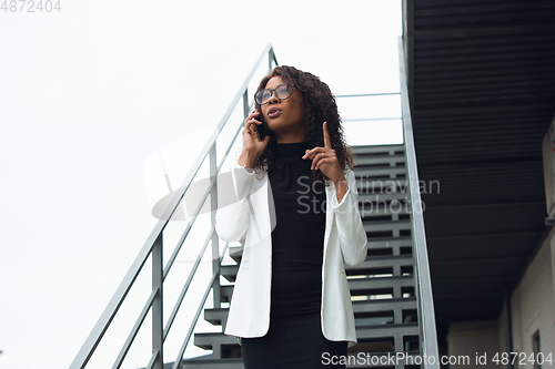 Image of Beautiful african-american well-dressed businesswoman looks confident and busy, successful