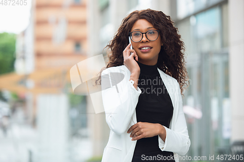 Image of Beautiful african-american well-dressed businesswoman looks confident and busy, successful