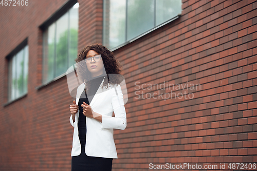 Image of Beautiful african-american well-dressed businesswoman looks confident and busy, successful