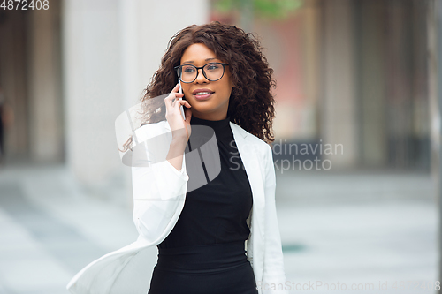 Image of Beautiful african-american well-dressed businesswoman looks confident and busy, successful