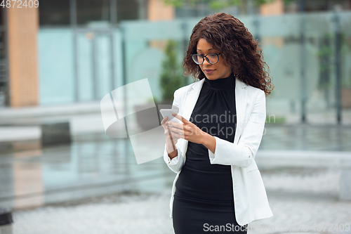 Image of Beautiful african-american well-dressed businesswoman looks confident and busy, successful