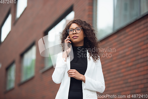 Image of Beautiful african-american well-dressed businesswoman looks confident and busy, successful