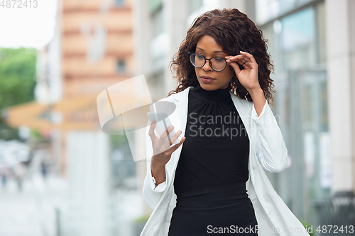 Image of Beautiful african-american well-dressed businesswoman looks confident and busy, successful