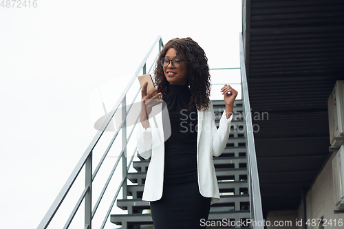 Image of Beautiful african-american well-dressed businesswoman looks confident and busy, successful