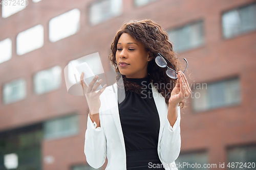 Image of Beautiful african-american well-dressed businesswoman looks confident and busy, successful