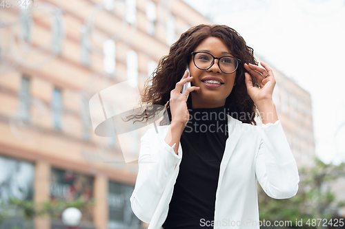 Image of Beautiful african-american well-dressed businesswoman looks confident and busy, successful