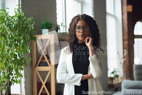 Image of Beautiful african-american well-dressed businesswoman looks confident and busy, successful