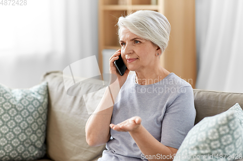 Image of senior woman calling on smartphone at home