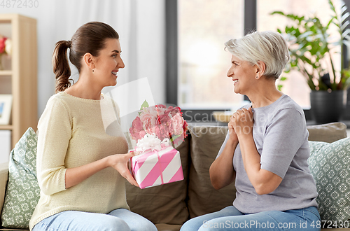 Image of adult daughter giving present to her senior mother