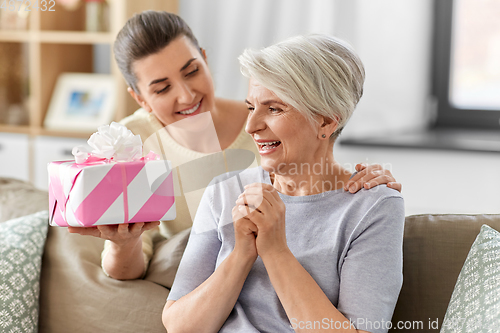 Image of adult daughter giving present to her senior mother