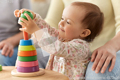 Image of happy baby girl playing with toy pyramid at home